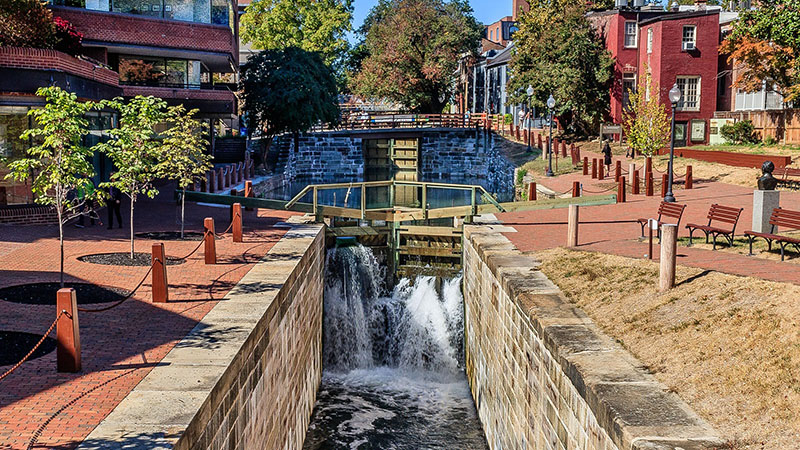 The canal's watered lock site surrounded by buildings and a red brick colonnade.