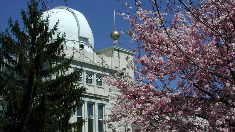 US Naval Observatory in Washington, DC set behind a blooming cherry tree and a Douglas Fir tree.