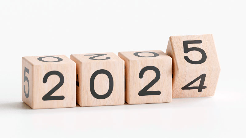 Wooden blocks with the numbers 2, 0, 2, and 5 on them. the last one has the appearance of rolling from 4 to 5.